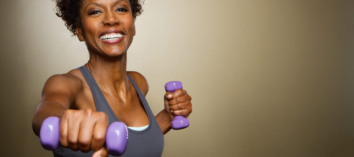 Smiling Fit African American woman lifting weights