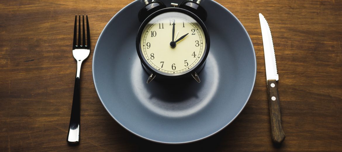 a clock in a bowl with knife and fork aside